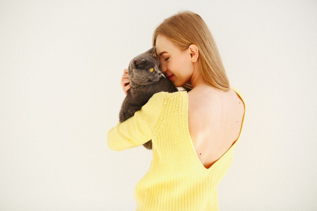 lady-in-yellow-dress-with-open-back-holds-grey-cat-on-her-shoulder_1304-3075